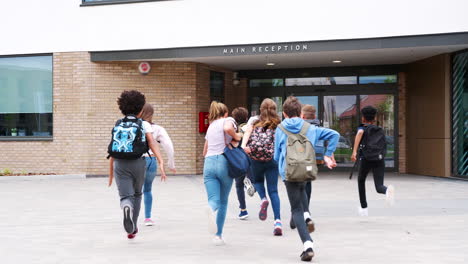Group-Of-High-School-Students-Running-Into-School-Building-At-Beginning-Of-Class