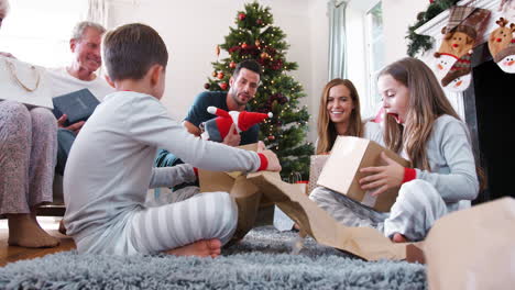 Drei-Generationen-Familie-Trägt-Pyjamas-In-Der-Lounge-Zu-Hause-Und-öffnet-Geschenke-Am-Weihnachtstag