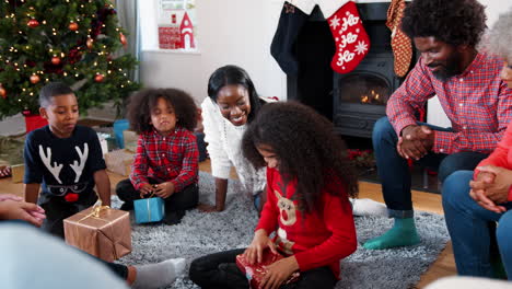 Tochter-öffnet-Geschenk,-Während-Die-Familie-Mit-Mehreren-Generationen-Gemeinsam-Weihnachten-Zu-Hause-Feiert