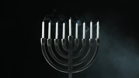 A-row-of-nine-white-candles-burning-in-a-menorah-are-blown-out,-front-view