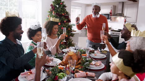Black-grandfather-standing-to-make-a-speech-and-a-toast-at-the-head-of-the-family-Christmas-dinner-table,-front-view