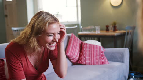 Young-adult-woman-laughing-while-talking-with-a-friend-in-the-lounge-room-at-a-pub,-close-up