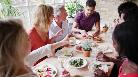 Eine-Multiethnische-Gruppe-Erwachsener-Freunde-Gemischten-Alters,-Die-Gemeinsam-Tapas-Zum-Mittagessen-In-Einem-Kleinen-Restaurant-Essen,-Erhöhte-Aussicht