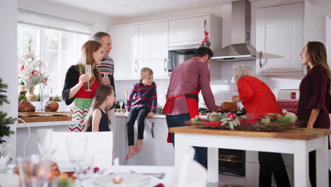 Mann-Holt-Truthahn-Aus-Dem-Ofen,-Während-Eine-Familie-Mit-Mehreren-Generationen-Zu-Hause-Gemeinsam-Am-Tisch-Zum-Weihnachtsessen-Sitzt