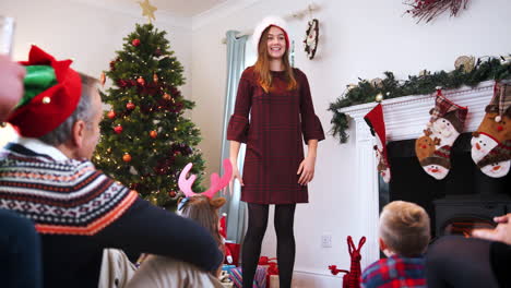 Teenage-Girl-Acting-Out-Mime-As-Multi-Generation-Family-Play-Game-Of-Christmas-Charades-At-Home-Together