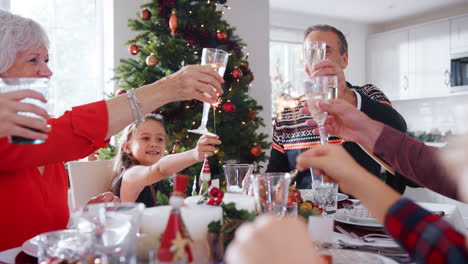 Mehrgenerationenfamilie-Sitzt-Am-Tisch-Und-Stößt-An,-Bevor-Sie-Zu-Hause-Gemeinsam-Das-Weihnachtsessen-Isst