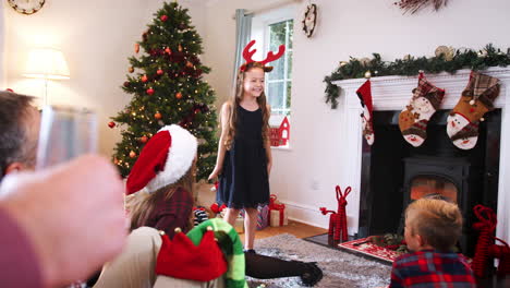 Junges-Mädchen-Spielt-Pantomime,-Während-Eine-Familie-Aus-Mehreren-Generationen-Zu-Hause-Gemeinsam-Weihnachtsscharaden-Spielt