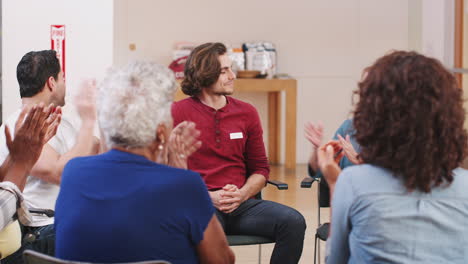 Man-Standing-To-Address-Self-Help-Therapy-Group-Meeting-In-Community-Center