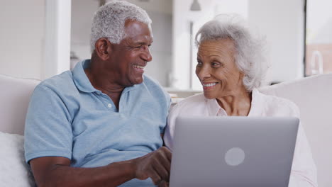 Älteres-Paar-Sitzt-Zu-Hause-Auf-Dem-Sofa-Und-Benutzt-Gemeinsam-Einen-Laptop