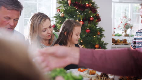 Mehrgenerationenfamilie-Sitzt-Am-Tisch-Und-Genießt-Gemeinsam-Das-Weihnachtsessen-Zu-Hause