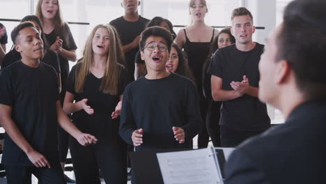 Male-And-Female-Students-Singing-In-Choir-With-Teacher-At-Performing-Arts-School