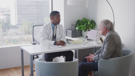 Senior-Male-Patient-Having-Hospital-Consultation-With-Doctor-In-Office