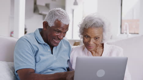 Älteres-Paar-Sitzt-Zu-Hause-Auf-Dem-Sofa-Und-Benutzt-Gemeinsam-Einen-Laptop