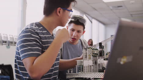 Zwei-Männliche-College-Studenten-Mit-Laptop-Baumaschine-Im-Naturwissenschaftlichen-Robotik--Oder-Ingenieurunterricht