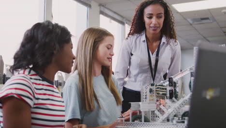 Teacher-With-Two-Female-College-Students-Building-Machine-In-Science-Robotics-Or-Engineering-Class