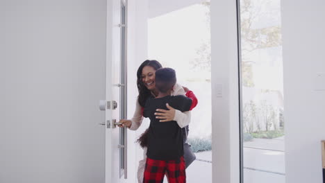 Children-Wearing-Pajamas-Greeting-And-Hugging-Working-Businesswoman-Mother-As-She-Returns-Home-From-Work