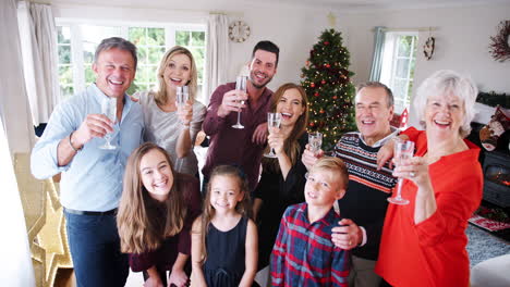 Portrait-Of-Multi-Generation-Family-And-Friends-Celebrating-With-Champagne-At-Christmas-House-Party