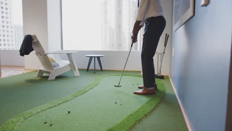 Businessman-Practicing-Golf-On-Indoor-Putting-Surface-In-Office