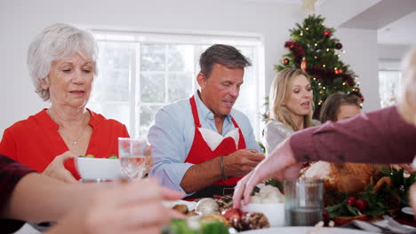 Mehrgenerationenfamilie-Sitzt-Am-Tisch-Und-Genießt-Gemeinsam-Das-Weihnachtsessen-Zu-Hause