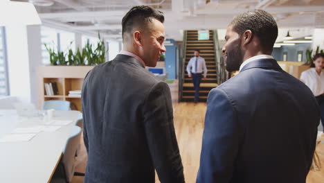 Two-Businessmen-Meeting-And-Shaking-Hands-In-Modern-Open-Plan-Office