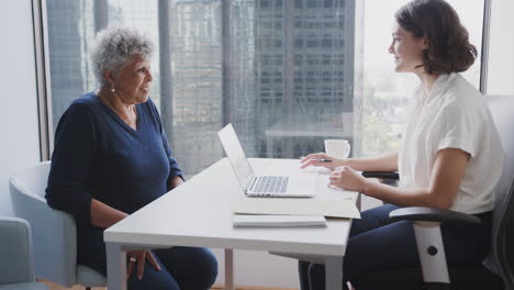 Senior-Woman-Meeting-With-Female-Financial-Advisor-In-Office