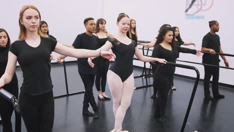 Estudiantes-Masculinos-Y-Femeninos-De-La-Escuela-De-Artes-Escénicas-Ensayando-Ballet-En-El-Estudio-De-Danza-Usando-Barra
