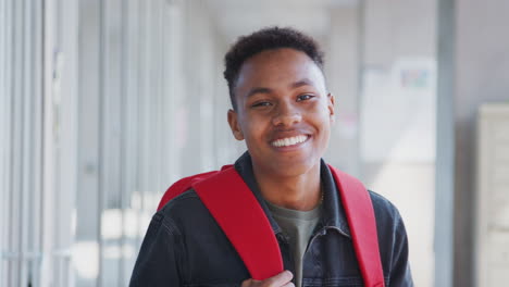 Portrait-Of-Smiling-Male-University-Student-With-Backpack-In-Corridor-Of-College-Building
