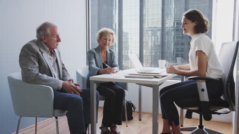 Senior-Couple-Signing-Document-In-Meeting-With-Female-Financial-Advisor-In-Office