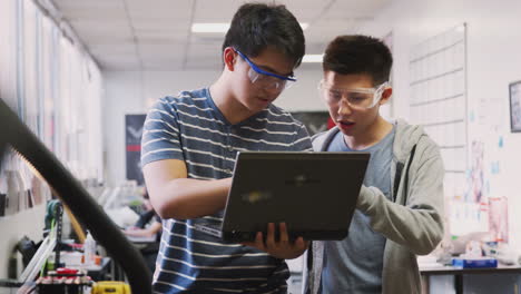 Two-Male-College-Students-Using-Laptop-Computer-In-Science-Robotics-Or-Engineering-Class