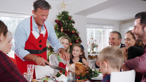 Man-Carving-Turkey-As-Multi-Generation-Family-Sit-Around-Table-For-Christmas-Meal-At-Home-Together