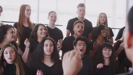 Male-And-Female-Students-Singing-In-Choir-With-Teacher-At-Performing-Arts-School