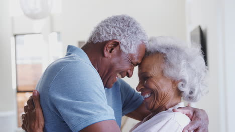 Profile-Shot-Loving-Senior-Couple-Hugging-At-Home-Together