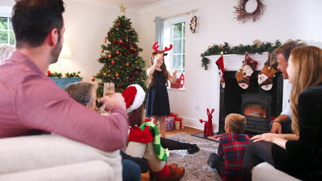 Junges-Mädchen-Spielt-Pantomime,-Während-Eine-Familie-Aus-Mehreren-Generationen-Zu-Hause-Gemeinsam-Weihnachtsscharaden-Spielt