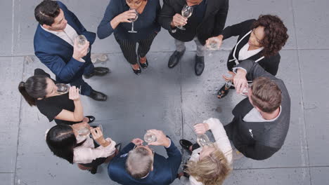 Overhead-Shot-Of-Business-Team-Celebrating-Success-With-Champagne-Toast-In-Modern-Office