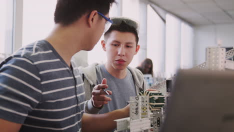 Zwei-Männliche-College-Studenten-Mit-Laptop-Baumaschine-Im-Naturwissenschaftlichen-Robotik--Oder-Ingenieurunterricht