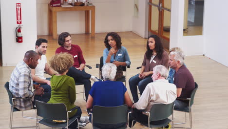 People-Sitting-In-Circle-Attending-Self-Help-Therapy-Group-Meeting-In-Community-Center