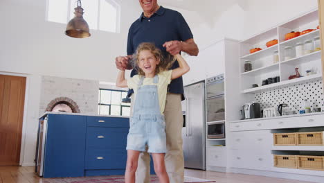 Granddaughter-Playing-Game-Walking-On-Grandfathers-Feet-At-Home