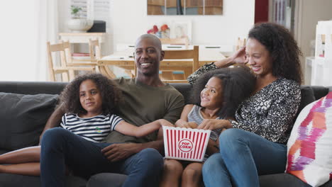 Familie-Sitzt-Zu-Hause-Auf-Dem-Sofa,-Isst-Popcorn-Und-Schaut-Gemeinsam-Einen-Film
