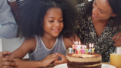 Familia-Multigeneracional-Celebrando-El-Cumpleaños-De-Sus-Nietas-En-Casa-Con-Pastel-Y-Velas