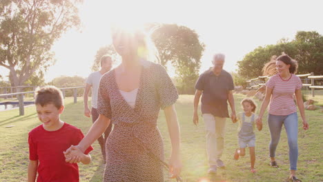 Multi-Generation-Family-Walking-In-Countryside-Against-Flaring-Sun