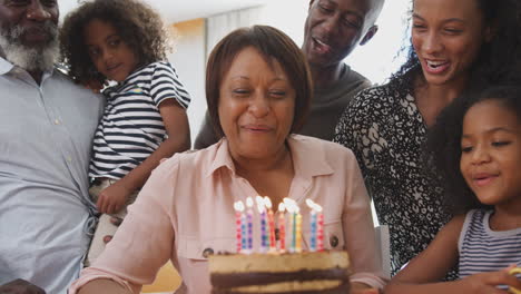 Mehrgenerationenfamilie-Feiert-Den-Geburtstag-Der-Großmutter-Zu-Hause-Mit-Kuchen-Und-Kerzen