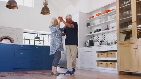 Älteres-Paar-Zu-Hause-Tanzt-Zusammen-In-Der-Küche