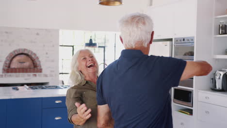 Älteres-Paar-Zu-Hause-Tanzt-Zusammen-In-Der-Küche