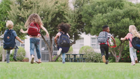 Rear-View-Of--Elementary-School-Pupils-Running-Across-Field-At-Break-Time