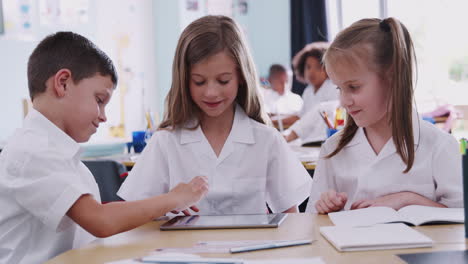 Drei-Grundschüler-In-Uniform-Nutzen-Ein-Digitales-Tablet-Am-Schreibtisch