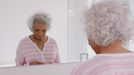 Senior-Woman-In-Bathroom-Taking-Vitamin-Supplement-Tablets