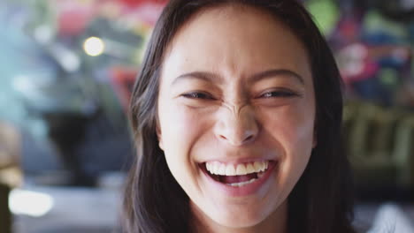 Junge-Asiatische-Frau-Lächelt-Und-Lacht-Vor-Einem-Wandgemälde-In-Die-Kamera,-Kopfaufnahme,-Nahaufnahme