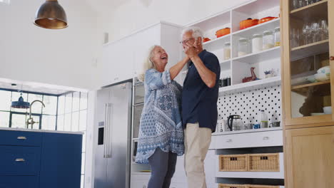 Senior-Couple-At-Home-Dancing-In-Kitchen-Together