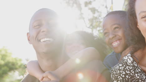 Outdoor-Portrait-Of-Smiling-Family-In-Garden-At-Home-Against-Flaring-Sun