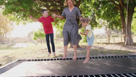 Mother-Playing-With-Children-On-Outdoor-Trampoline-In-Garden